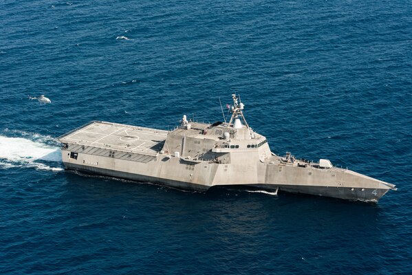 An unmanned helicopter flies over a ship in the ocean.