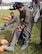 Maj. Chris Lamkey (standing) and Maj. Clay Holland (sitting), 170th Group members assigned to Offutt Air Force Base, Nebraska, don anti-exposure suits while participating in water survival and rescue training July 14, 2018. The suits are worn by aircrew in the eventuality they must be in water where the temperature is below 60 F. The air crew members were briefed on the availability and use of tools contained in their survival gear before putting academics and theory to the test in the waters of a local lake.