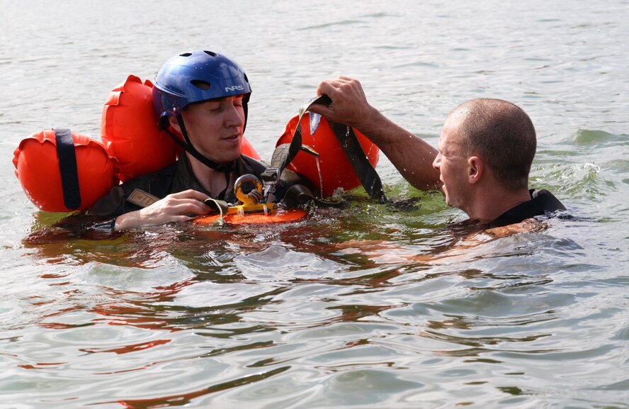 Maj. Kevin Selin, member of the 170th Group assigned to Offutt Air Force Base, Nebraska, is instructed in the use of an extraction tool by Staff Sgt. Neal Troyer, 55th Operational Support Squadron Squadron Survival Evasion Resistance Escape specialist, while participating in water survival and rescue training July 14, 2018. The hands-on water instruction included donning cold-water exposure suits; inflating and swimming with inflatable life preservers; and boarding and utilizing a 20-person survival raft.