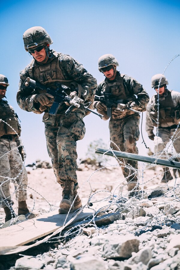 Marines in the Infantry Officer Course breach an obstacle during a live fire training exercise at Range 410A aboard the Marine Corps Air Ground Combat Center, Twentynine Palms, Calif., June 9, 2018. The Purpose of IOC is to train and educate newly selected infantry and ground intelligence officers in leadership, infantry skills, character required to serve as infantry platoon commanders in the operating forces. (U.S. Marine Corps photo by Lance Cpl. William Chockey)