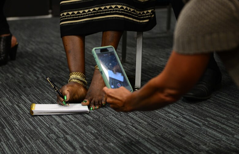 Tawana Williams, motivational speaker, demostrates how she signs her name to attendees July 16, 2018, at Columbus Air Force Base, Mississippi. Born without arms, Williams learned how to care for herself, and later on her daughter, with her feet. (U.S. Air Force Photo by Airman 1st Class Beaux Hebert)