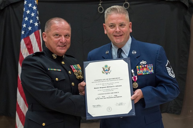 Master Sgt. Michael Johnson from the 27th Aerial Port Squadron receives his certificate of retirement from retired United States Marine Corps Lt. Col. John Peterson July 14.  Johnson retires with 31 years of service. (Air Force Photo/Master Sgt. Eric Amidon)