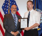 IMAGE: DAHLGREN, Va. (July 19, 2018) - Clinton Winfrey holds a plaque reproduction of the patent certificate he just received from John Fiore, Naval Surface Warfare Center Dahlgren Division (NSWCDD) technical director. Winfrey - along with co-inventors Benjamin Baldwin and Dr. Mary Ann Cummings - were among 32 patent holders honored before family, friends and colleagues at the NSWCDD Patent Awards ceremony. The 'Modular Model and Simulation Architecture' invented and patented by Winfrey, Baldwin and Cummings provides a computer architecture that greatly reduces the cost and effort to create a modeling and simulation software. The warfighter is provided with quicker and easier construction of modeling and simulation programs to design and improve systems.  (U.S. Navy photo by Ryan DeShazo/Released)