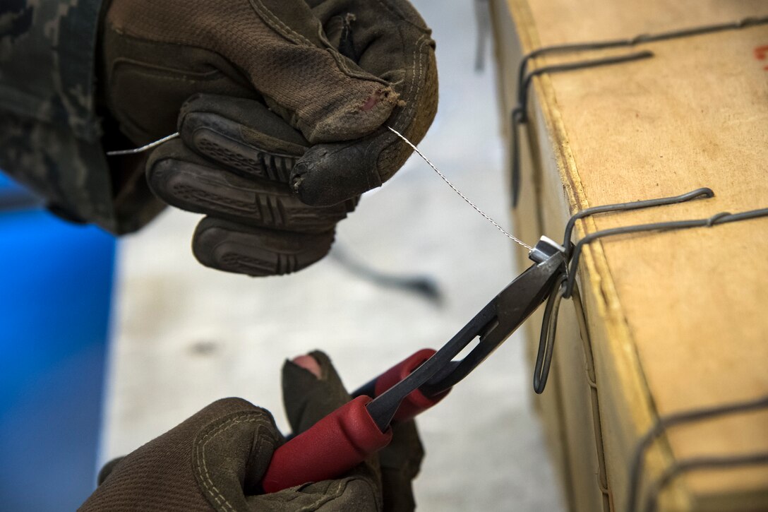 An Airman from the 23d Maintenance Squadron (MXS), ties a support wire to the lock of a munitions crate, July 10, 2018, at Moody Air Force Base, Ga. Munitions inspectors enhance Moody’s combat capabilities by inspecting and approving safe and serviceable ammo. (U.S. Air Force photo by Airman 1st Class Eugene Oliver)