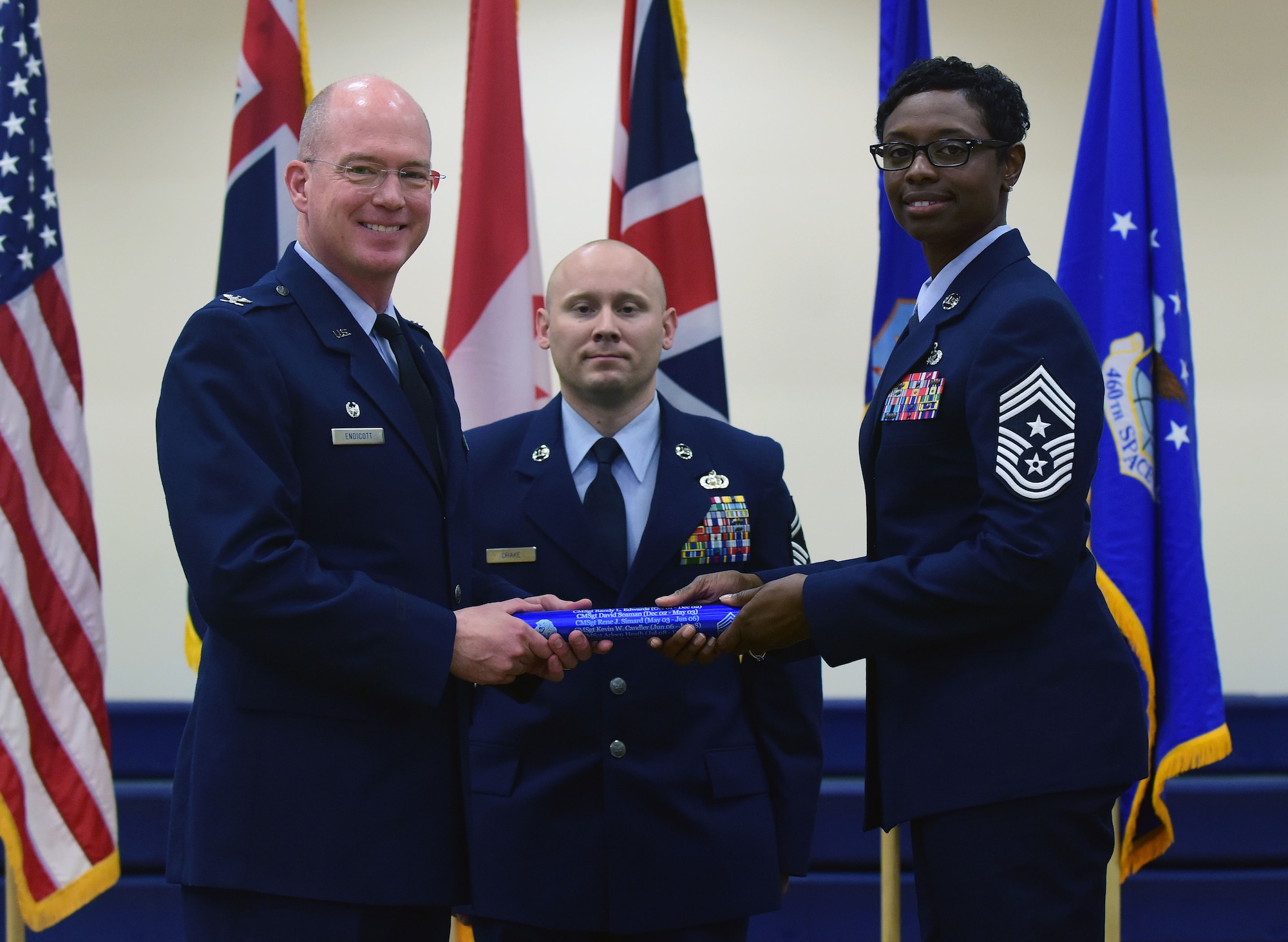 Chief Master Sgt. Tamar Dennis, 460th Space Wing command chief, accepts the baton from Col. Troy L. Endicott, 460th SW commander, symbolizing the change of leadership on Buckley Air Force Base, Colorado, July 20, 2018.