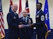 Chief Master Sgt. Tamar Dennis, 460th Space Wing command chief, accepts the baton from Col. Troy L. Endicott, 460th SW commander, symbolizing the change of leadership on Buckley Air Force Base, Colorado, July 20, 2018.