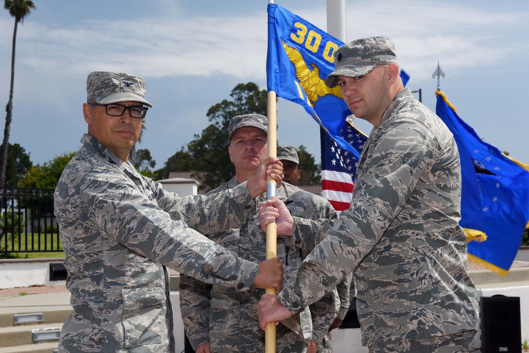 Col. Curtis Hernandez, 30th Operations Group commander, hands the guide on to Lt. Col. Brian Chatman, 1st Air and Space Test Squadron commander, during the 30th Launch Group deactivation ceremony on July 20, 2018, at Vandenberg Air Force Base, Calif. The 30th Space Wing inactivated the 30th LCG, merging their range responsibilities and personnel with the 30th OG. (U.S. Air Force photo by Tech. Sgt. Jim Araos/Released)