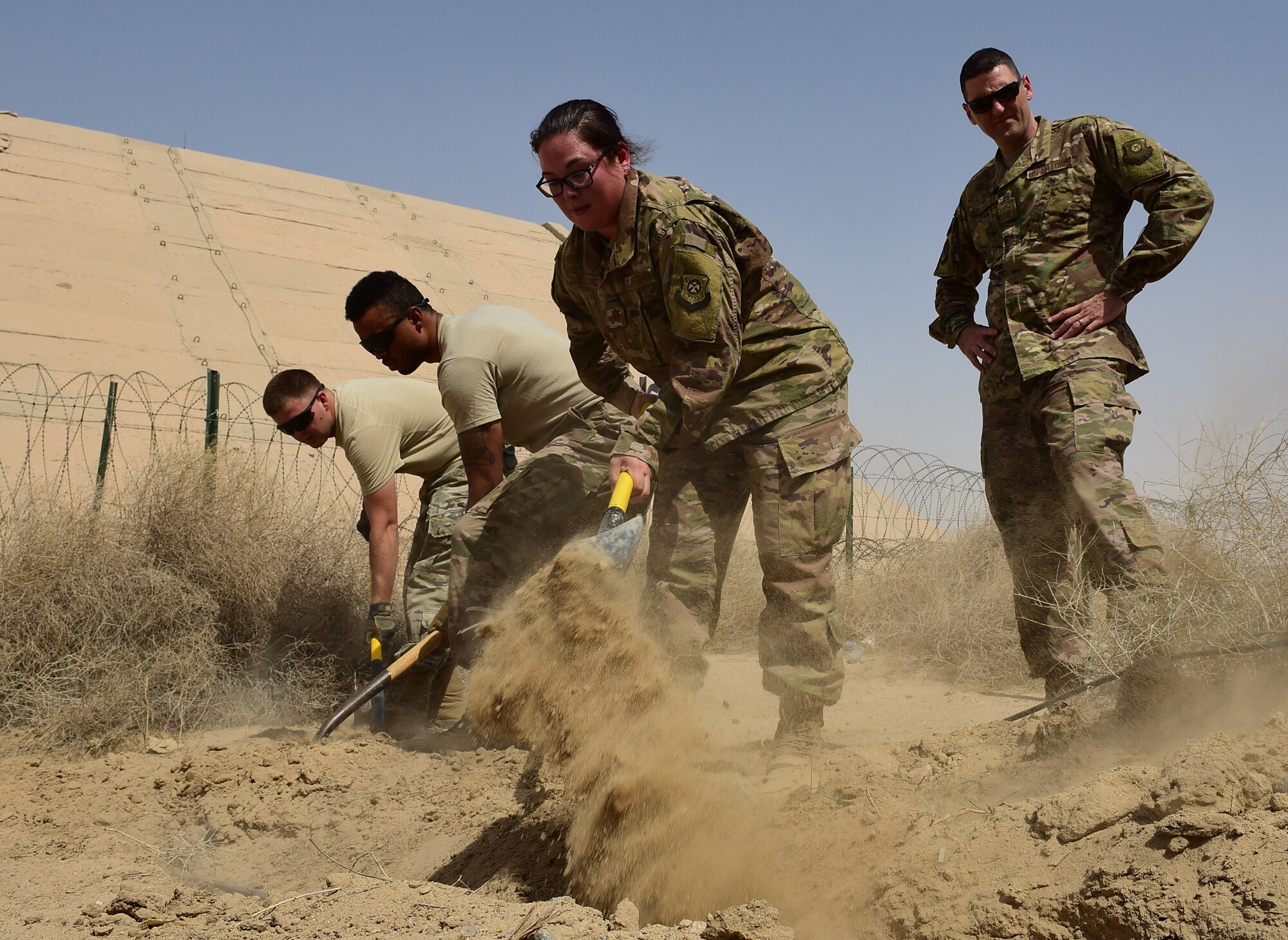 Airmen cover a cable with dirt
