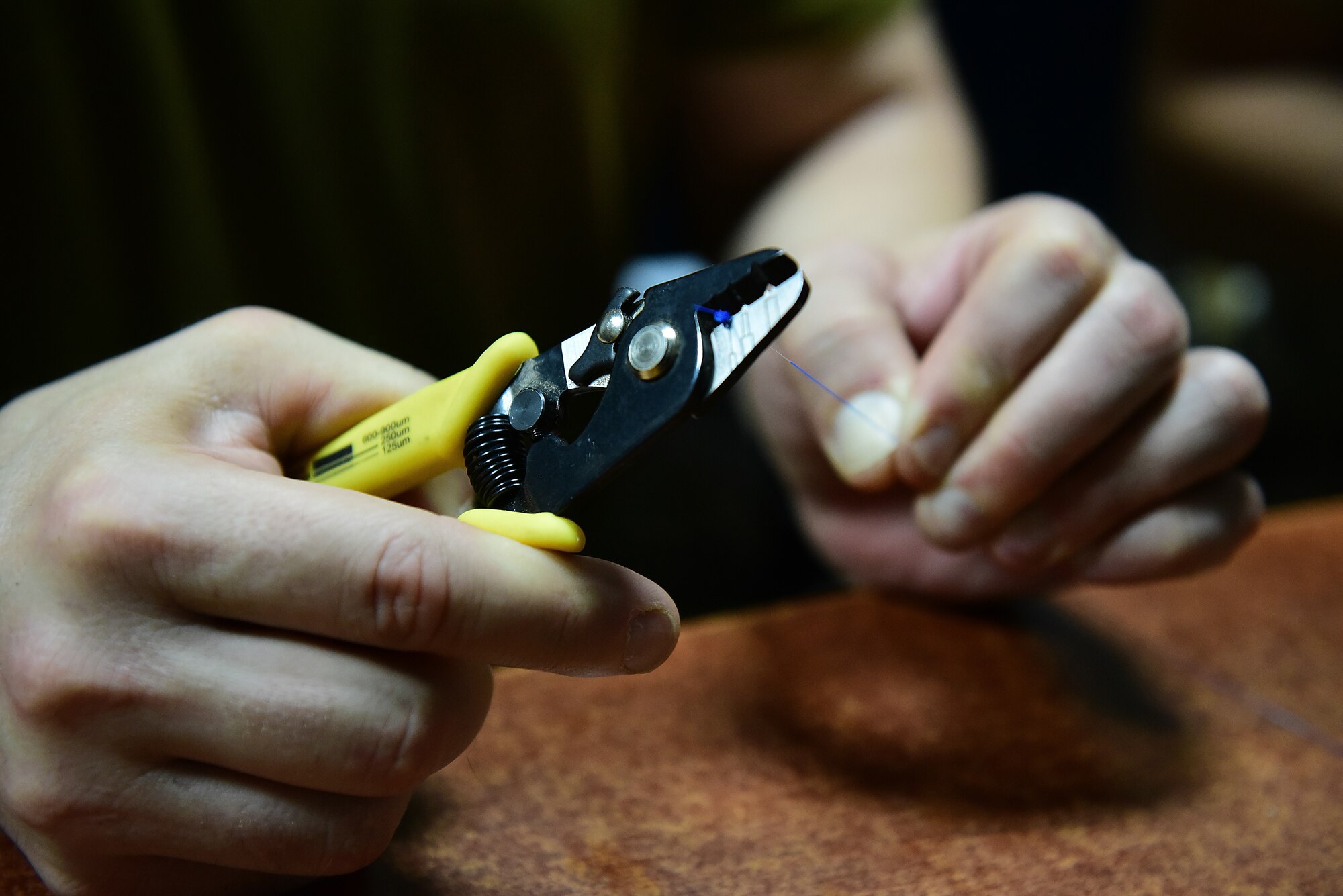 An airman cuts a wire with scissors