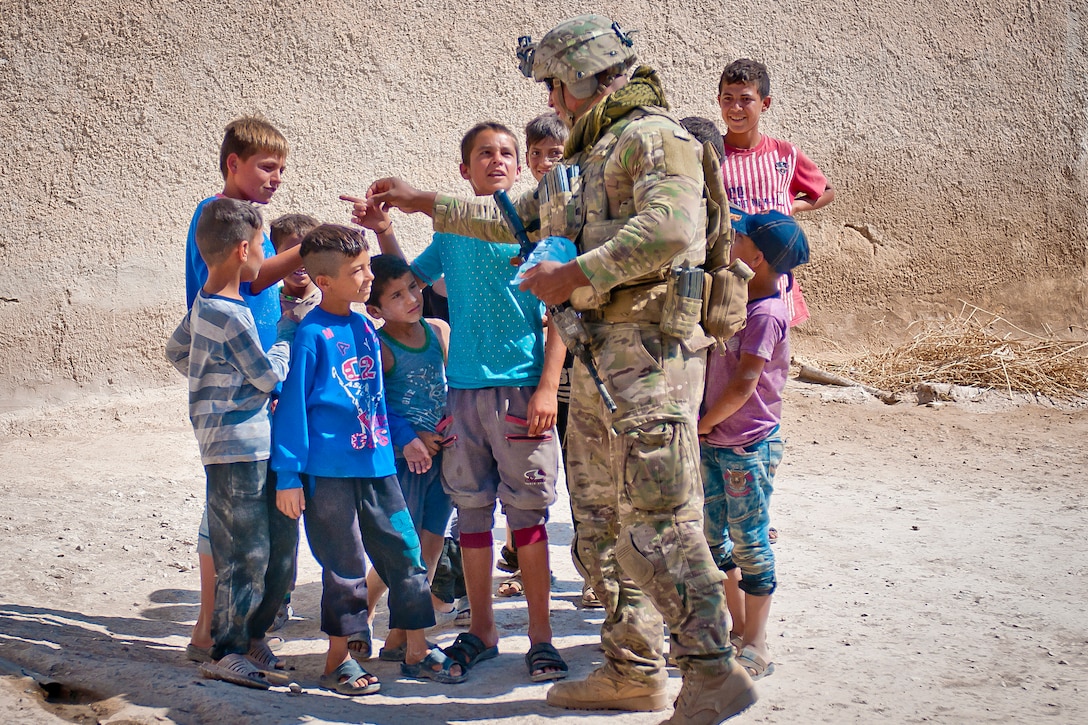 A soldier stands with a group of children.