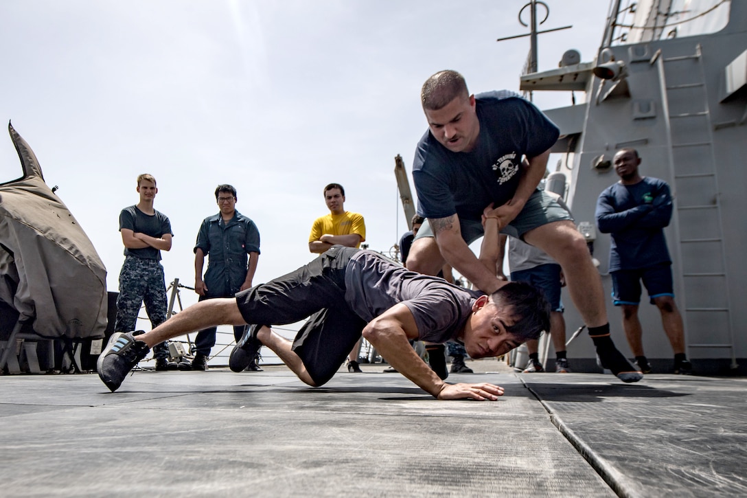 A sailor forces another sailor to the ground.