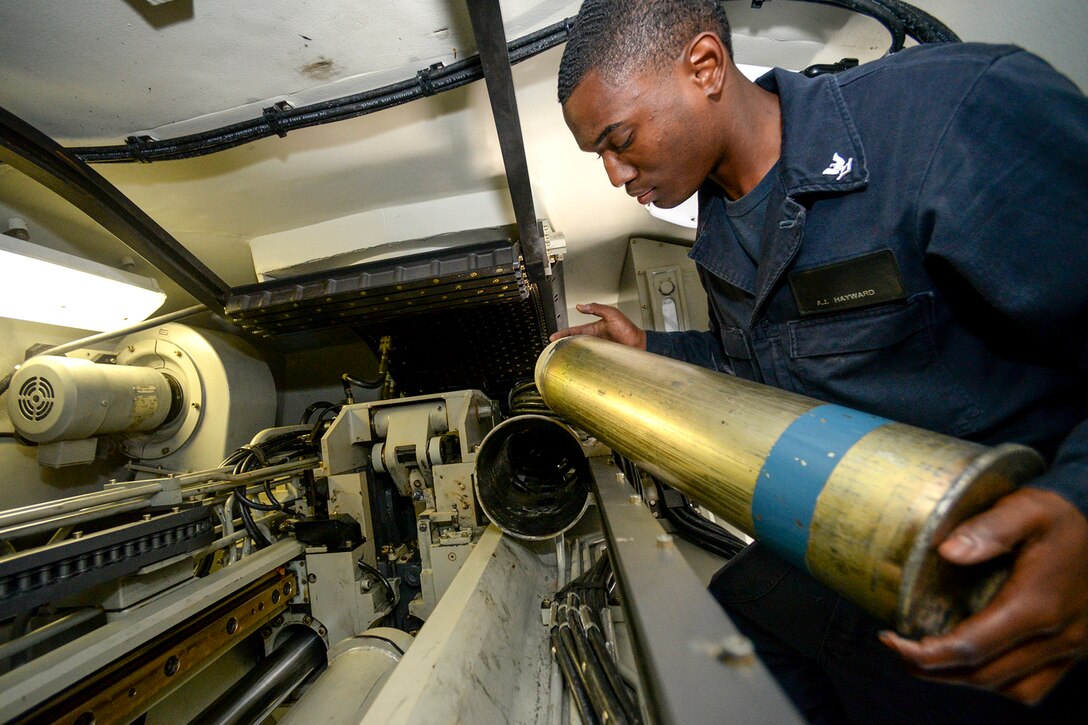 A sailor removes a tester round from a gun.