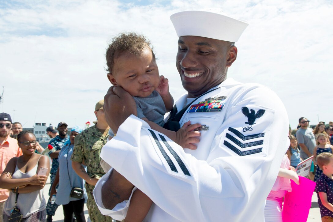 A sailor holds a baby.