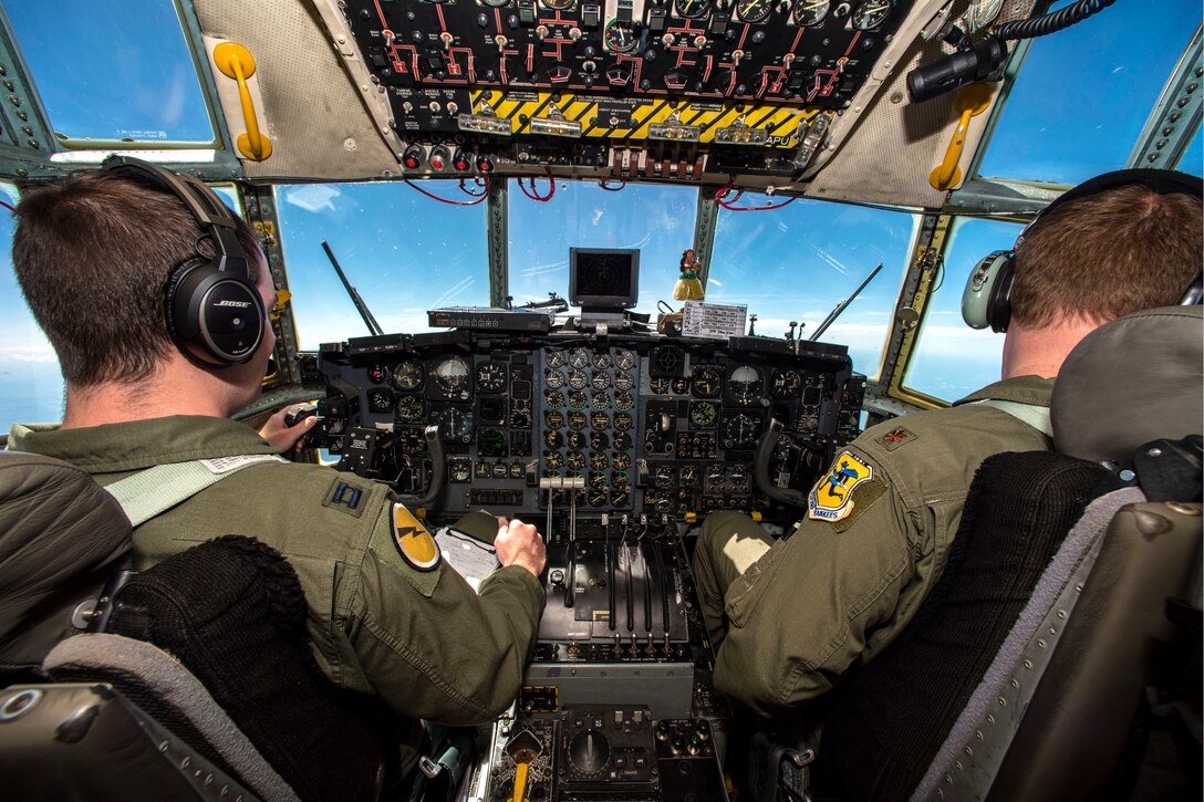 Two airmen sit behind the controls of an aircraft while flying.