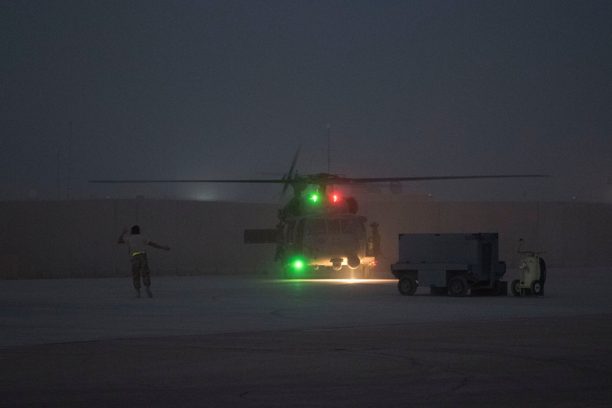 An Airman with the 801st Expeditionary Maintenance Squadron directs an HH-60 Pave Hawk after landing, July 5, 2018, at Al Asad Air Base, Iraq.