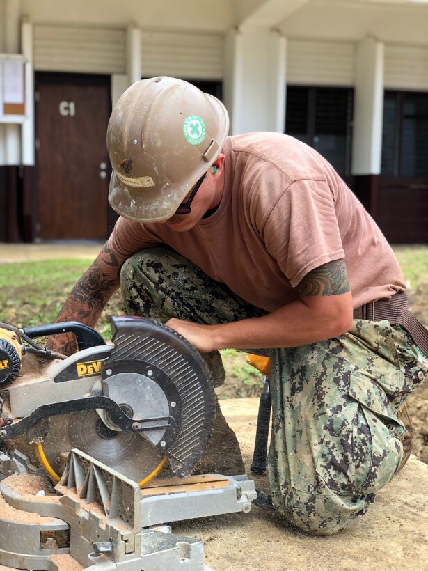 A sailor uses a chop saw to cut blocks for trusses.