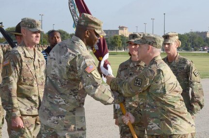 Lt. Col. Corey J. Plowden (left) accepts the unit colors from Col. Clinton W. Schreckhise, 32nd Medical Brigade commander, while outgoing commander Lt. Col. Caryn R. Vernon looks on.