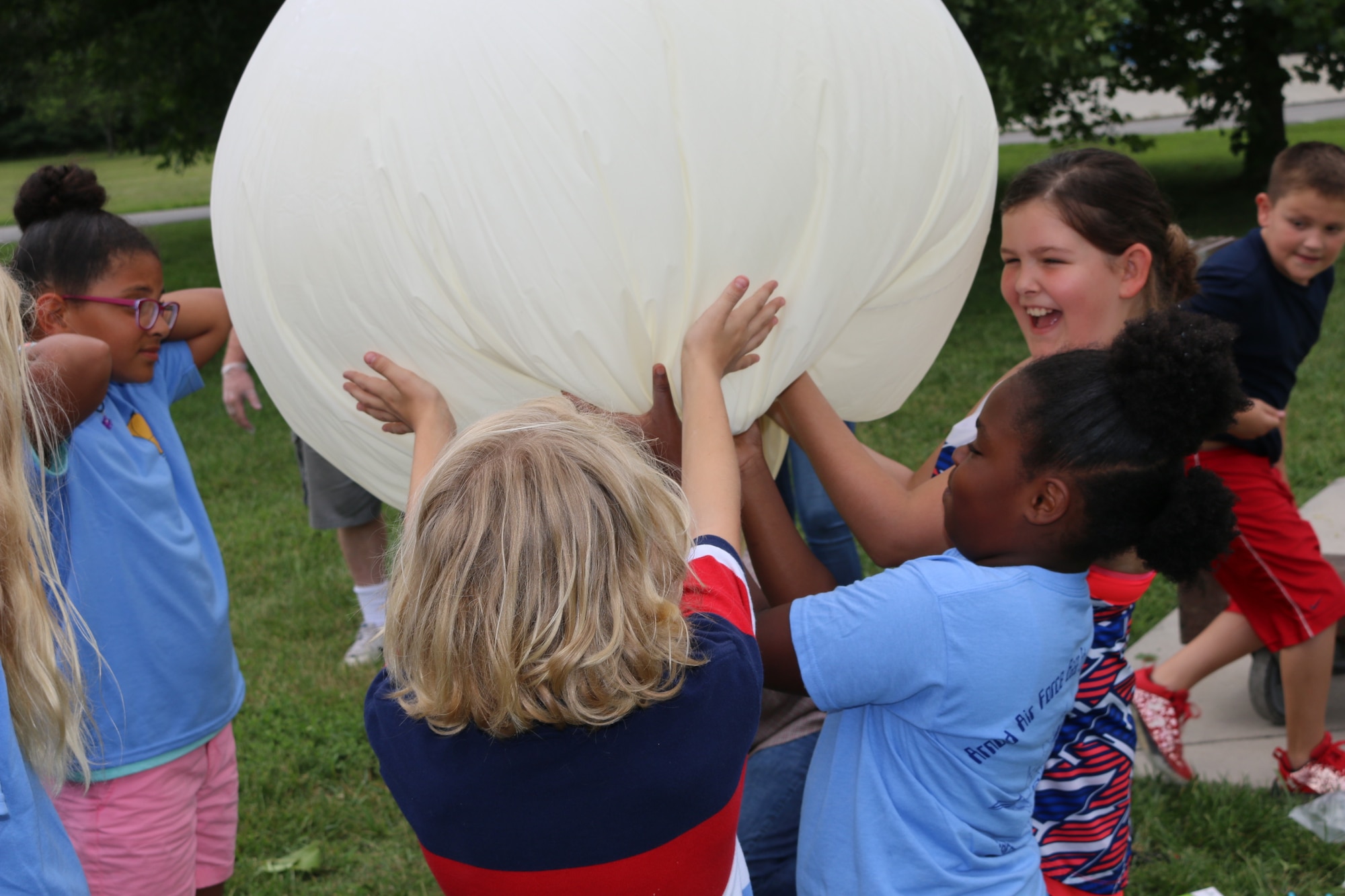Participants in the Hands-On Science Center Air Force STEM Summer Camp offer a helping hand as a high-altitude balloon is inflated. The balloon was launched on June 19 from the grounds of the HOSC as part of the Summer Camp program. (U.S. Air Force photo/Bradley Hicks)