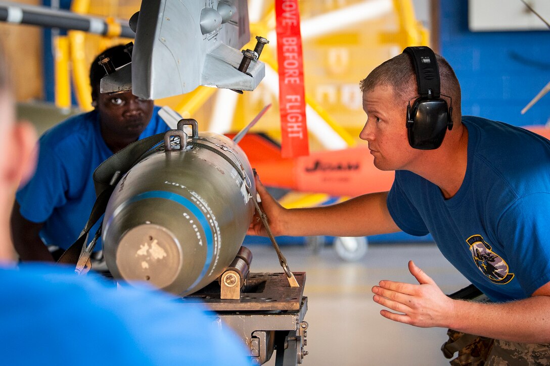 Airmen load a bomb onto an aircraft.