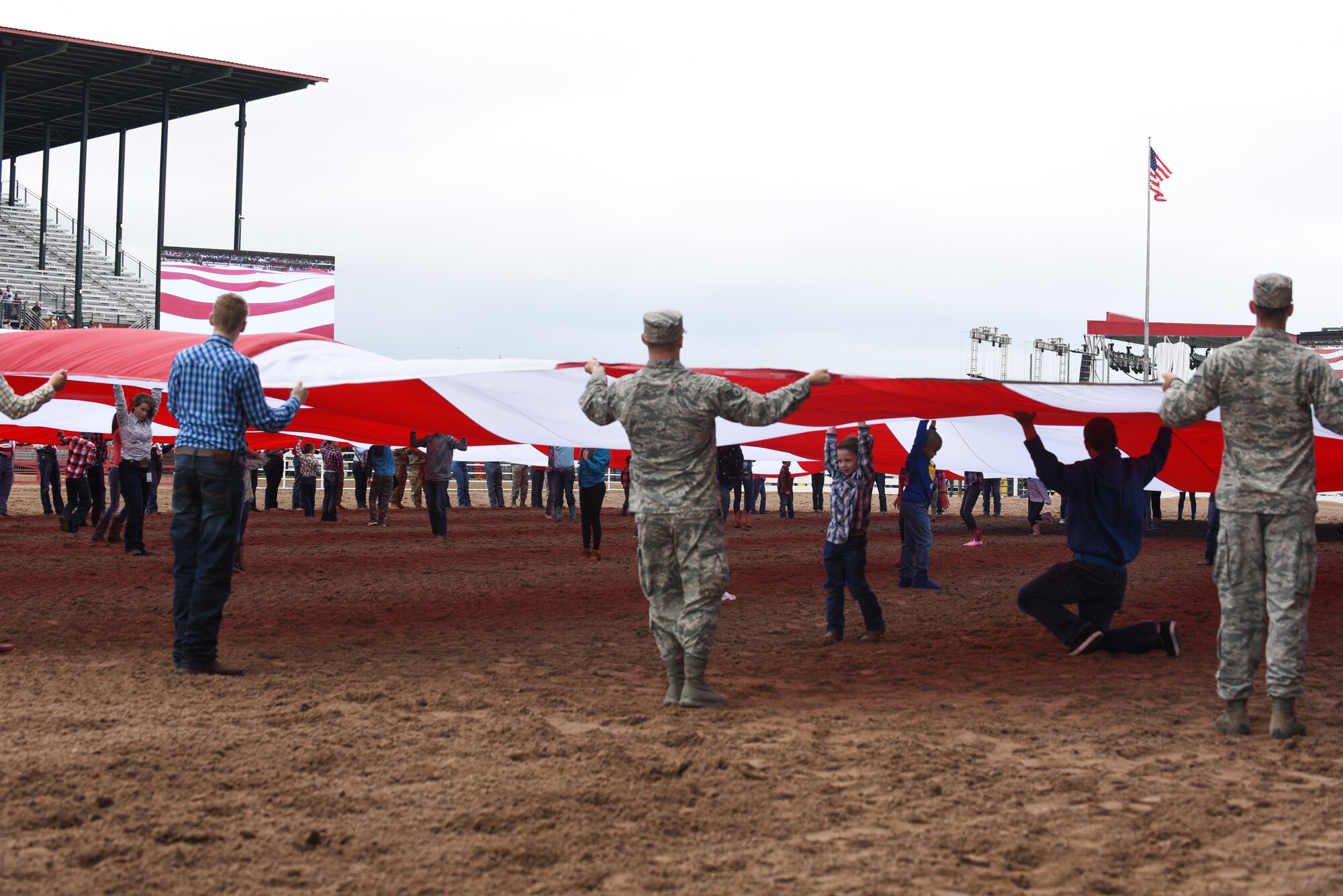 Children from the community stand under the American flag to keep it off the ground during Military Monday at Frontier Park in Cheyenne, Wyo., July 23, 2018. The flag presentation is an annual tradition at Cheyenne Frontier Days. This year marks the 151st anniversary of F.E. Warren Air Force Base and the city of Cheyenne. F.E. Warren Air Force Base’s involvement during CFD provides an opportunity to showcase the everlasting relationship between the base and the local community. (U.S. Air Force photo by Airman 1st Class Abbigayle Wagner)