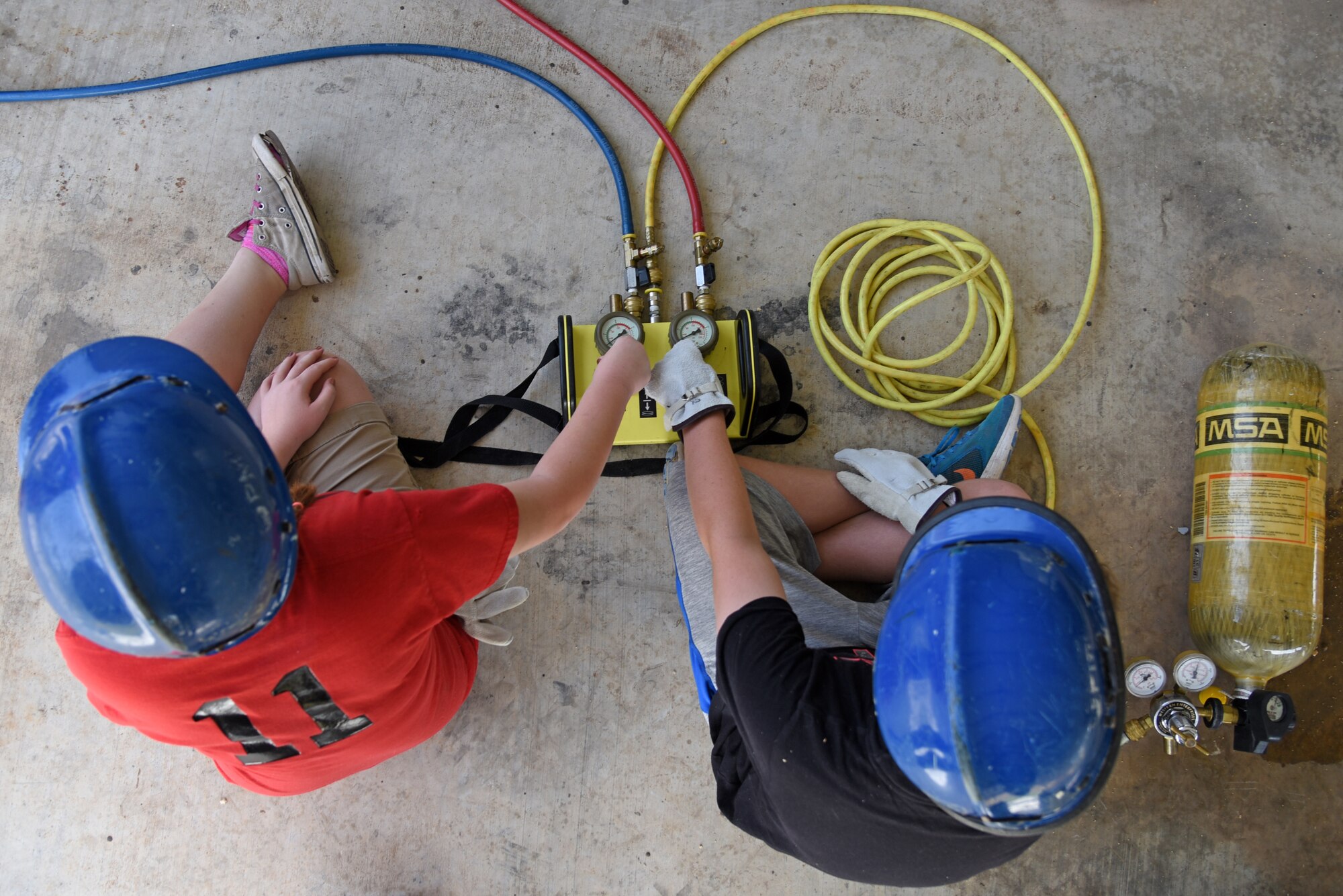 Junior firefighters, Evelynn Neddo and Nate Henry, control an air pressure switch during the Junior Firefighter Camp at the Fire Station on Goodfellow Air Force Base, Texas, July 17, 2018. The switch operates airbags that firefighters use to lift cars during an accident. (U.S. Air Force photo by Staff Sgt. Joshua Edwards/Released)