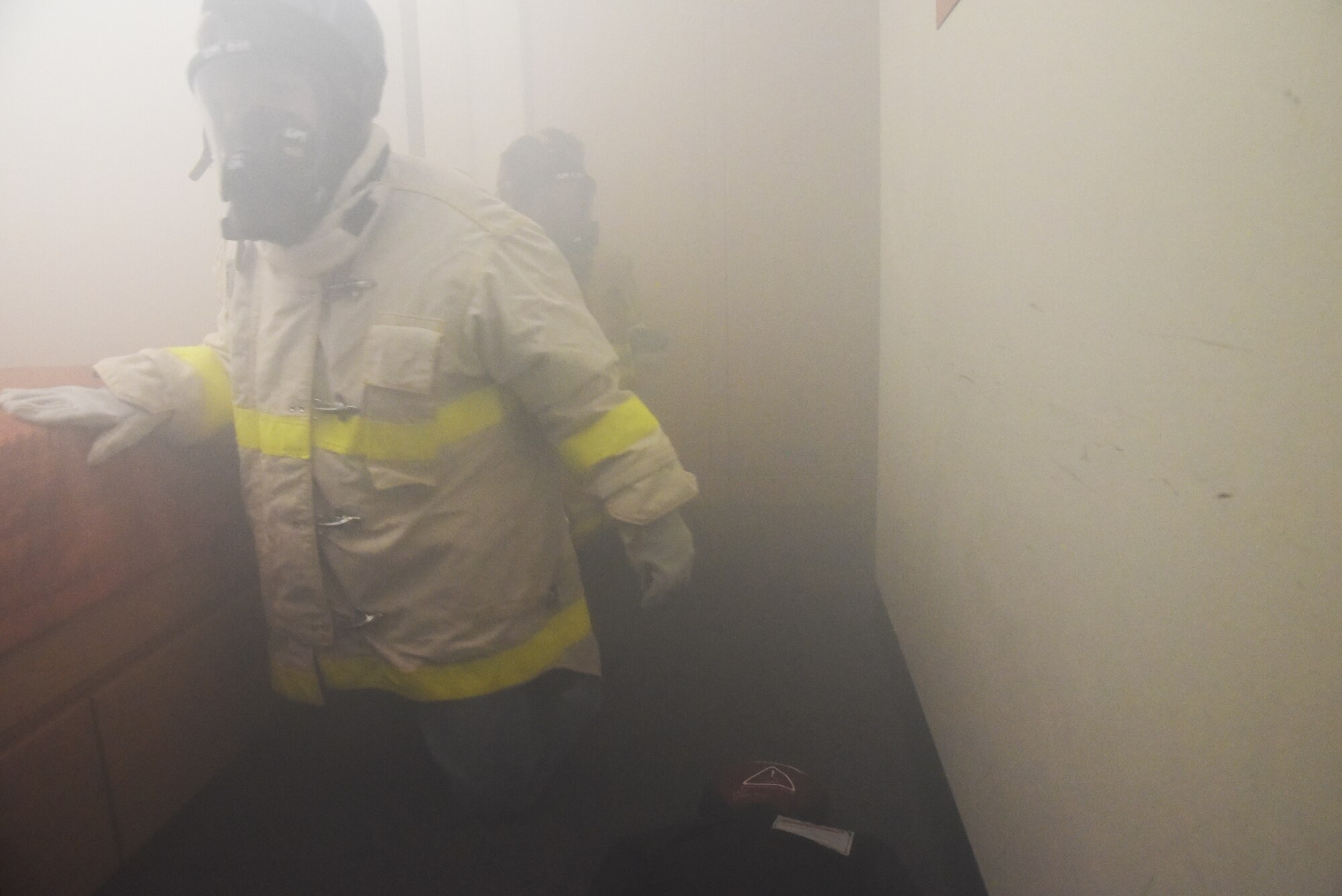 Junior firefighters, Quintin Scheffler and Lee Wright, search for a training dummy in a smoke filled room during the Junior Firefighter Camp at the Fire Station on Goodfellow Air Force Base, Texas, July 18, 2018. The practice of partnering up for search and rescue is used by firefighters in real world situations. (U.S. Air Force photo by Staff Sgt. Joshua Edwards/Released)