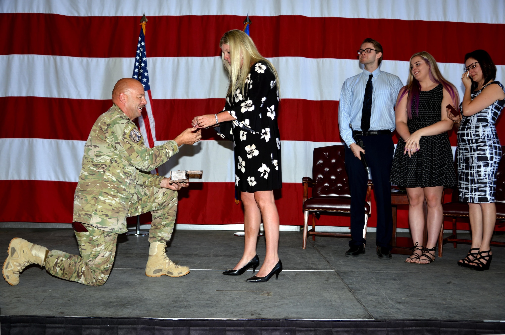 Chief Master Sgt. Robert Bean, USAF (ret.), presents his wife Jenny with a diamond ring during his retirement ceremony July 20 here. Bean, who served his final tour at Kirtland as the Commandant of the 351st Battlefield Airmen Training Squadron, also arranged for he and his wife to renew their vows on the spot during the ceremony. His children (left to right) Corey, Cailey and Christina witnessed the surprise proposal. He was showered with accolades from his Pararescue comrades and a grateful Air Force. (U.S. Air Force photo by Todd Berenger)