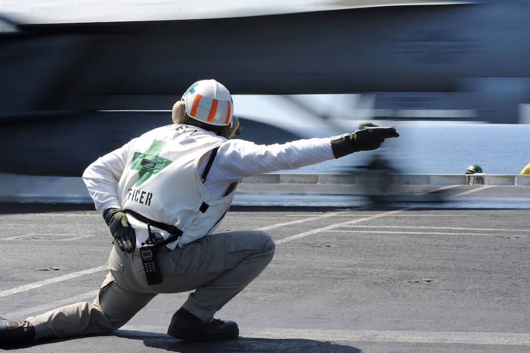 A sailor signals to launch an F/A-18 Super Hornet.