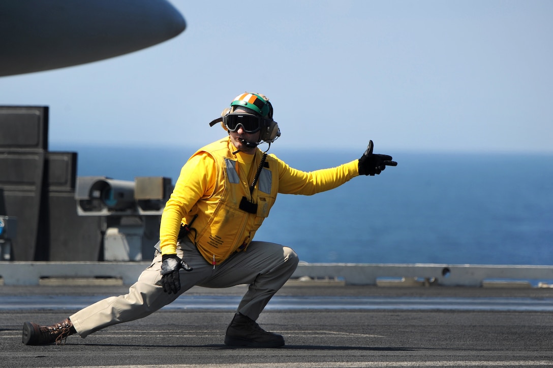 A sailor signals to launch an F/A-18 Super Hornet from the USS Harry S. Truman.