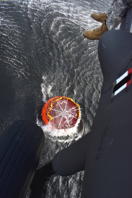 A UH-60 Black Hawk helicopter crew chiefs monitors the refilling of a bucket firefighting system.