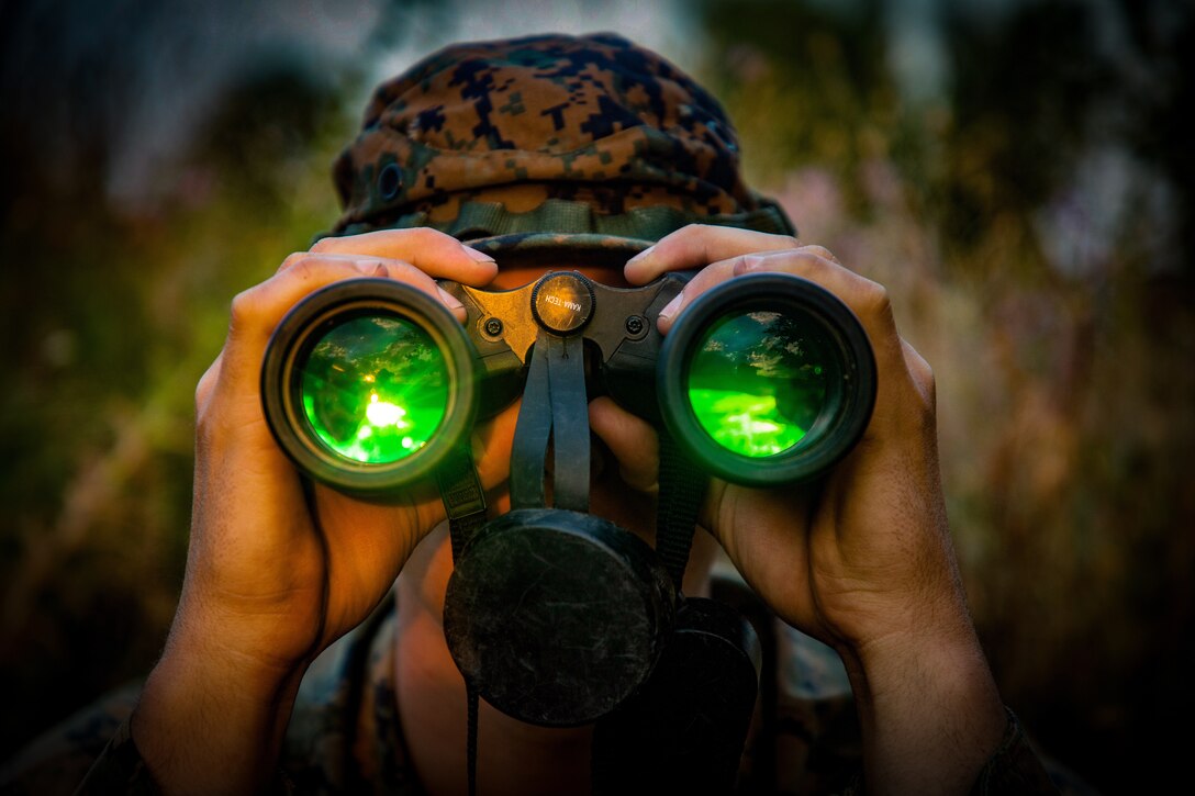 A U.S. Marine with Black Sea Rotational Force 18.1 observes a live-fire range through a pair of binoculars during a deployment for training exercise at Novo Selo Training Area, Bulgaria, July 2, 2018. Marines with Weapons Company, 1st Battalion, 6th Marine Regiment conducted five days of live-fire ranges, enhancing their operational capabilities. (U.S. Marine Corps Photo by Cpl. Alexander Sturdivant/Released)