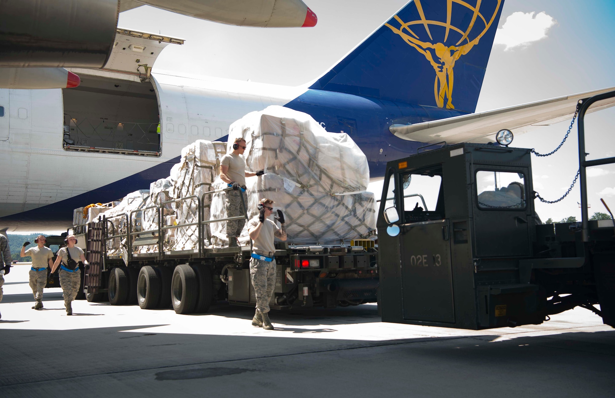 U.S. Airmen assigned to the 721st Aerial Port Squadron Ramp Services transport cargo offloaded from a Boeing 747 aircraft on Ramstein Air Base, Germany, July 18, 2018. Cargo that 721st APS Airmen process can include food, supplies, and ammunition, which supports locations across U.S. Central, Europe, and Africa Commands. (U.S. Air Force photo by Senior Airman Elizabeth Baker)