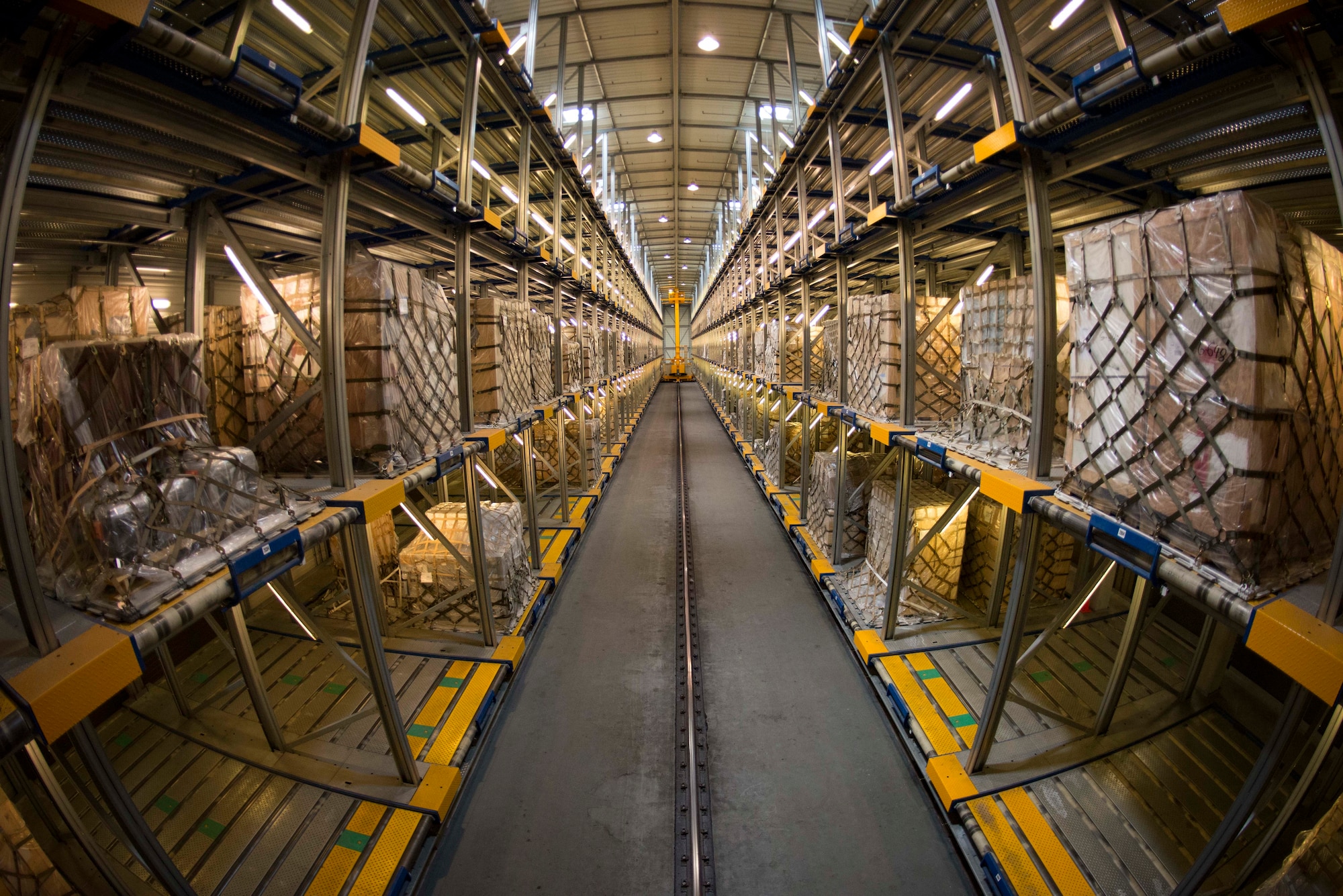 The 721st Aerial Port Squadron Mechanized Material Handling System receives cargo and places it in storage on Ramstein Air Base, Germany, July 18, 2018. The MMHS sorts and prioritizes pallets to expedite the cargo loading and unloading process. (U.S. Air Force photo by Senior Airman Elizabeth Baker)