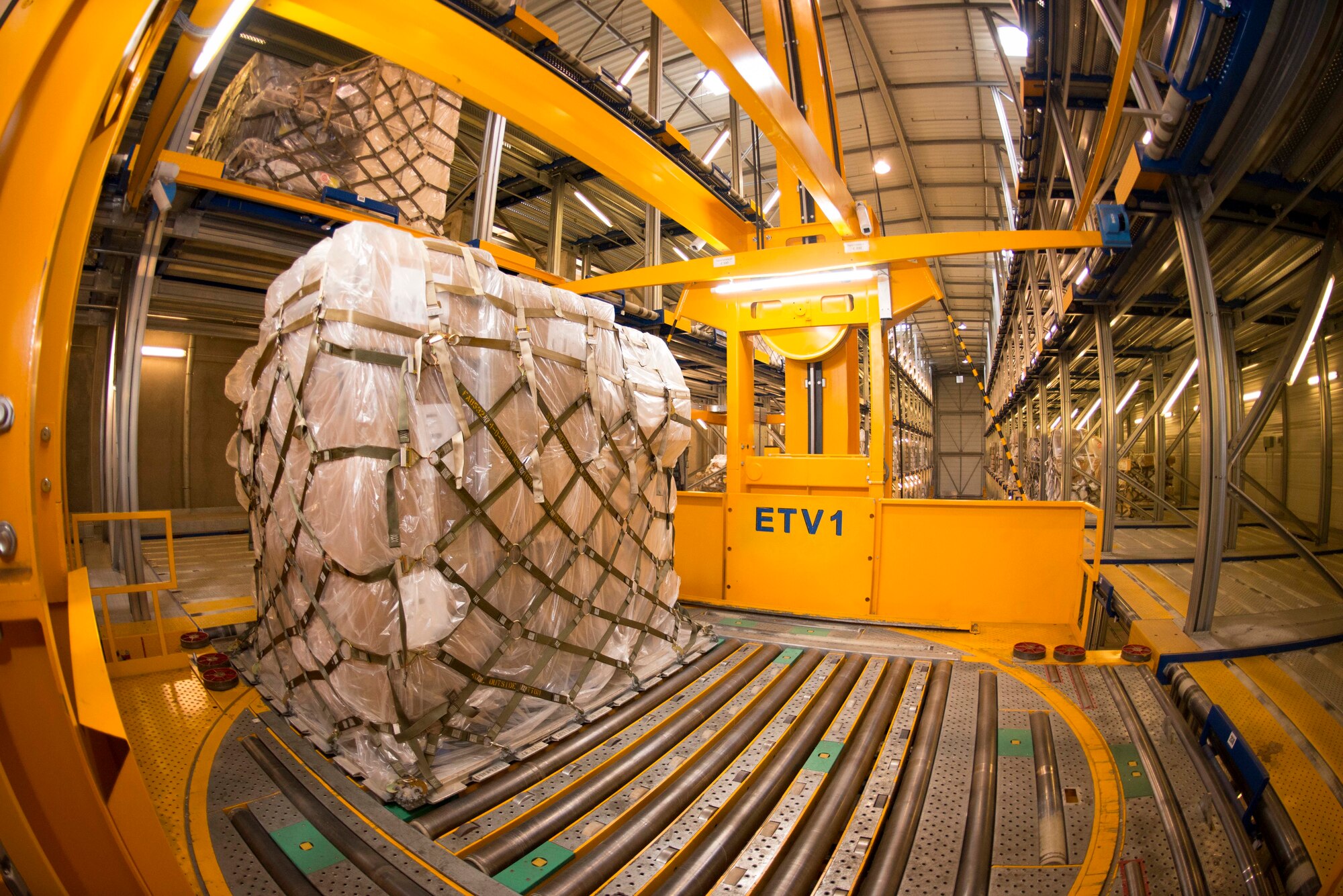 The 721st Aerial Port Squadron Mechanized Material Handling System places a cargo pallet in storage on Ramstein Air Base, Germany, July 18, 2018. The MMHS quickens pallet loading and unloading with its mechanized systems, which helps Ramstein's airlift mission continue with speed and efficiency. (U.S. Air Force photo by Senior Airman Elizabeth Baker)