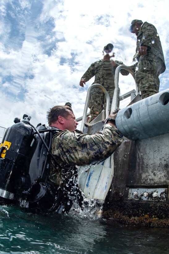 A Navy diver exits the water after conducting a training dive mission.