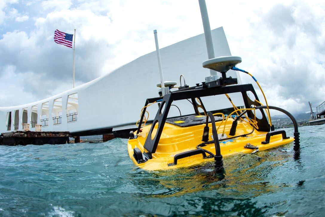 Navy divers use a hydrographic undersea vehicle to examine the hull of the USS Arizona Memorial.