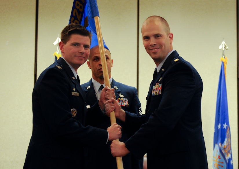 Maj. Andrew Mackenzie, right, 628th Communications Squadron incoming commander, accepts the 628th Mission Support Group guidon from Col. Rockie Wilson, left, 628th Mission Support Group commander, during a change of command ceremony at the Charleston Club, July 29, 2018. The 628th CS plans, installs, operates and maintains the full spectrum of joint communications systems and knowledge management services, aiding in the successful mission execution of Joint Base Charleston.