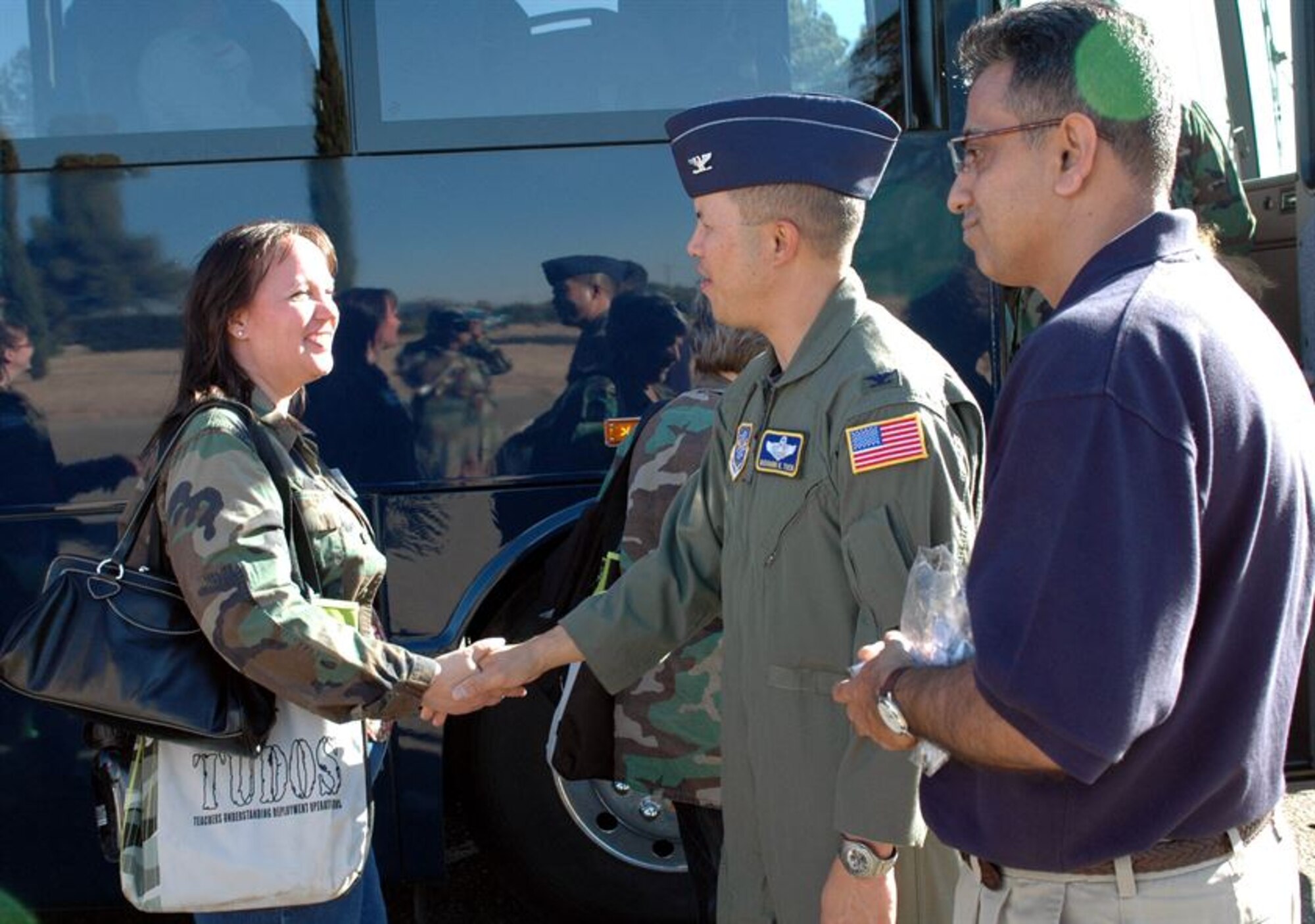 Col. GI Tuck, 60th Air Mobility Wing vice commander, congratulates a TUDOS participant upon completion of the mock deployment as Mustak Keval, TUDOS event coordinator, looks on. More than 60 teachers from the Travis Unified School District experience their very own mock deployment as Team Travis hosted its first-ever Teachers Understanding Deployment Operations event Oct. 3. (U.S. Air Force photo/Staff Sgt. Candy Knight)