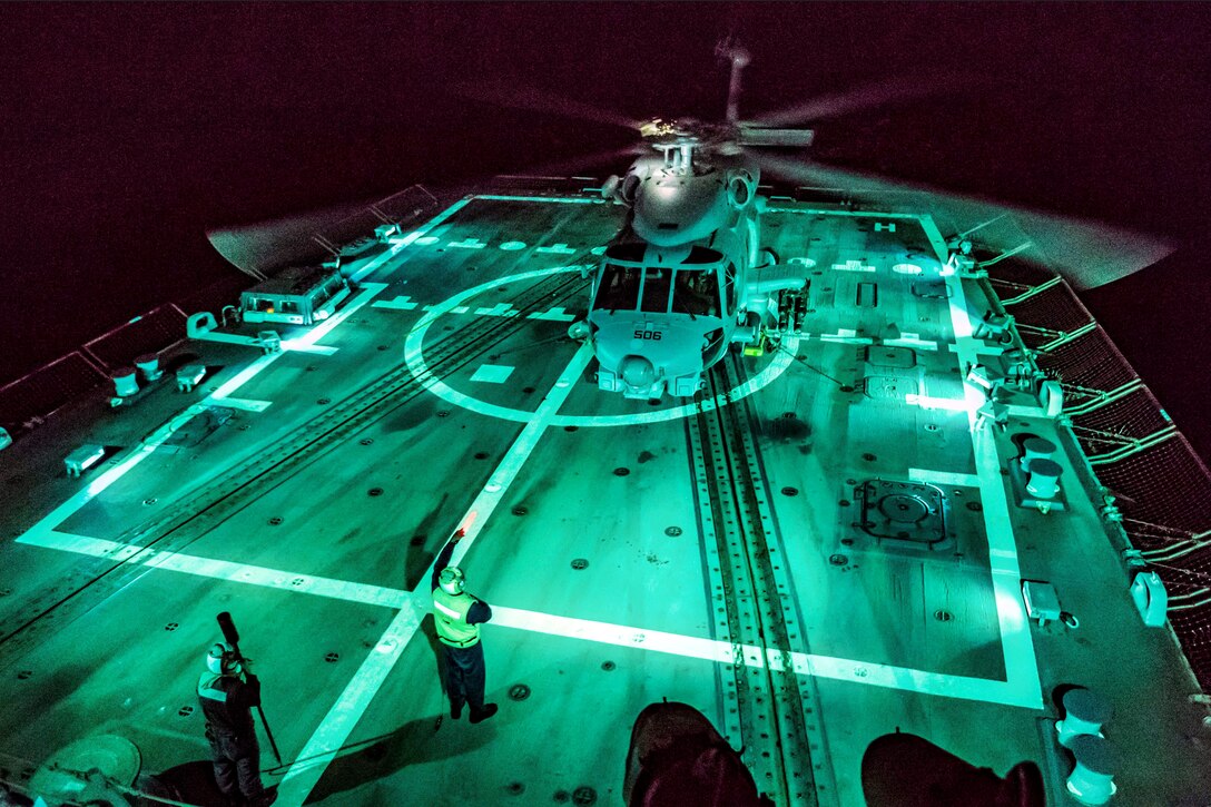 A helicopter sits on the deck of a ship