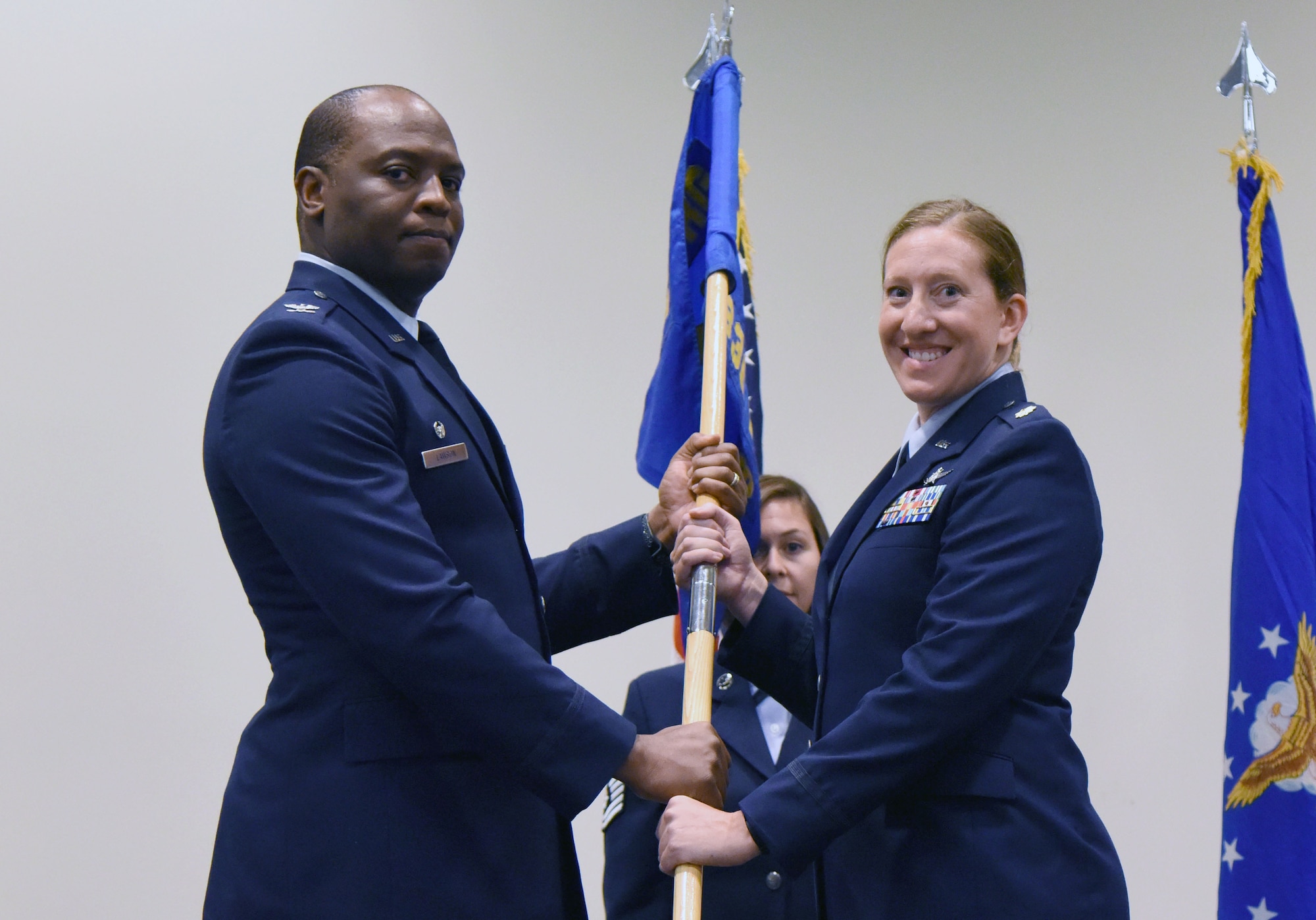 U.S. Air Force Col. Leo Lawson, Jr., 81st Training Group commander, passes the 336th Training Squadron guidon to Maj. Jill Heliker, 336th TRS commander, during the 336th TRS change of command ceremony in the Roberts Consolidated Aircraft Maintenance Facility at Keesler Air Force Base, Mississippi, July 23, 2018. The passing of the guidon is a ceremonial symbol of exchanging command from one commander to another. (U.S. Air Force photo by Kemberly Groue)