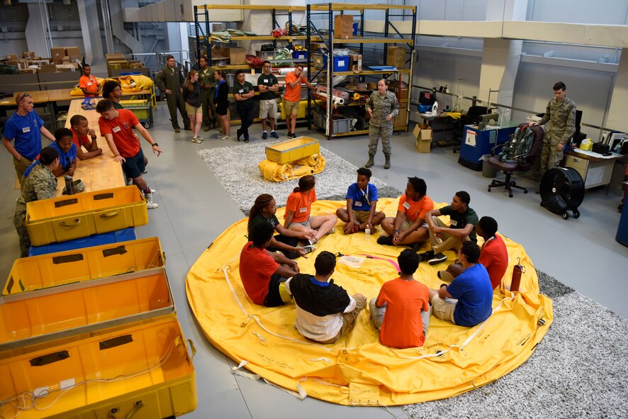 Students of the Aviation Character and Education Flight Program sit inside a life raft during their tour of Aircrew Flight Equipment July 19, 2018, at Dover Air Force Base, Del. The life rafts are able to hold 25 people and are a mandatory item aboard mobility aircraft. (U.S. Air Force photo by Airman 1st Class Zoe M. Wockenfuss)