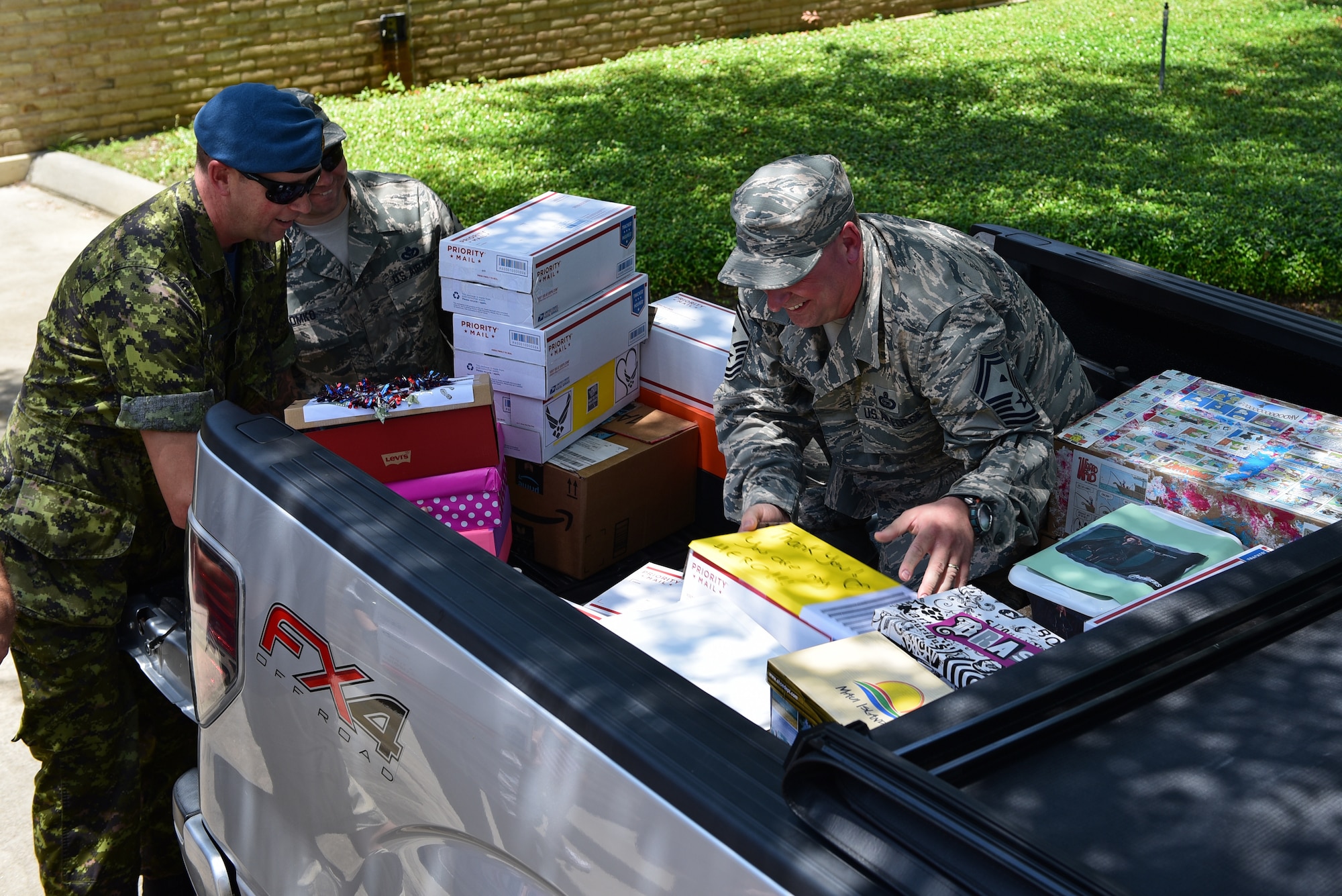 Senior enlisted members assigned to Tyndall Air Force Base, Florida, arrange care packages into the bed of a truck.