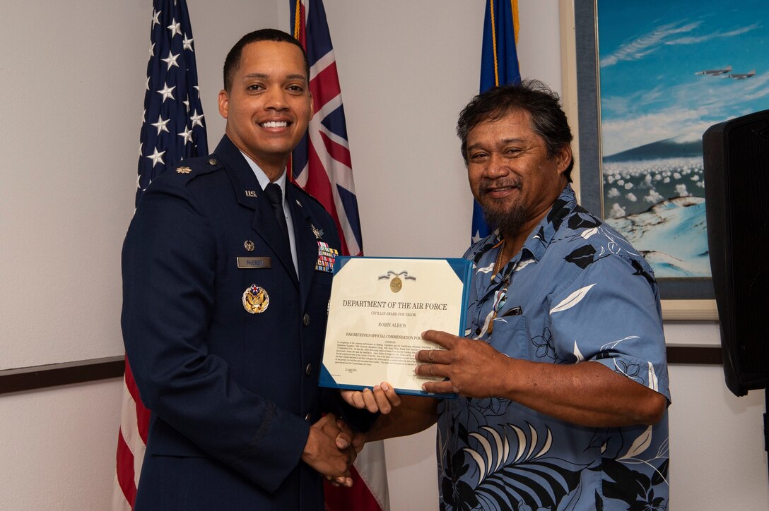 Lt. Col. Wade McGrew, 21st Space Operation sSquadron commander, presents the Air Force Civilian Award for Valor to Robin Albios, Detachment 3, 21st SOPS heating, ventilation and air conditioning specialist, at the Kaena Point Satellite Tracking Station, Hawaii, July 23, 2018. Two years ago, Albios provided medical aid to a state of Hawaii volunteer field crew member who suffered from smoke inhalation during a fire at the Kuaokala Game Management Area. (U.S. Air Force photo by Tech. Sgt. Heather Redman)