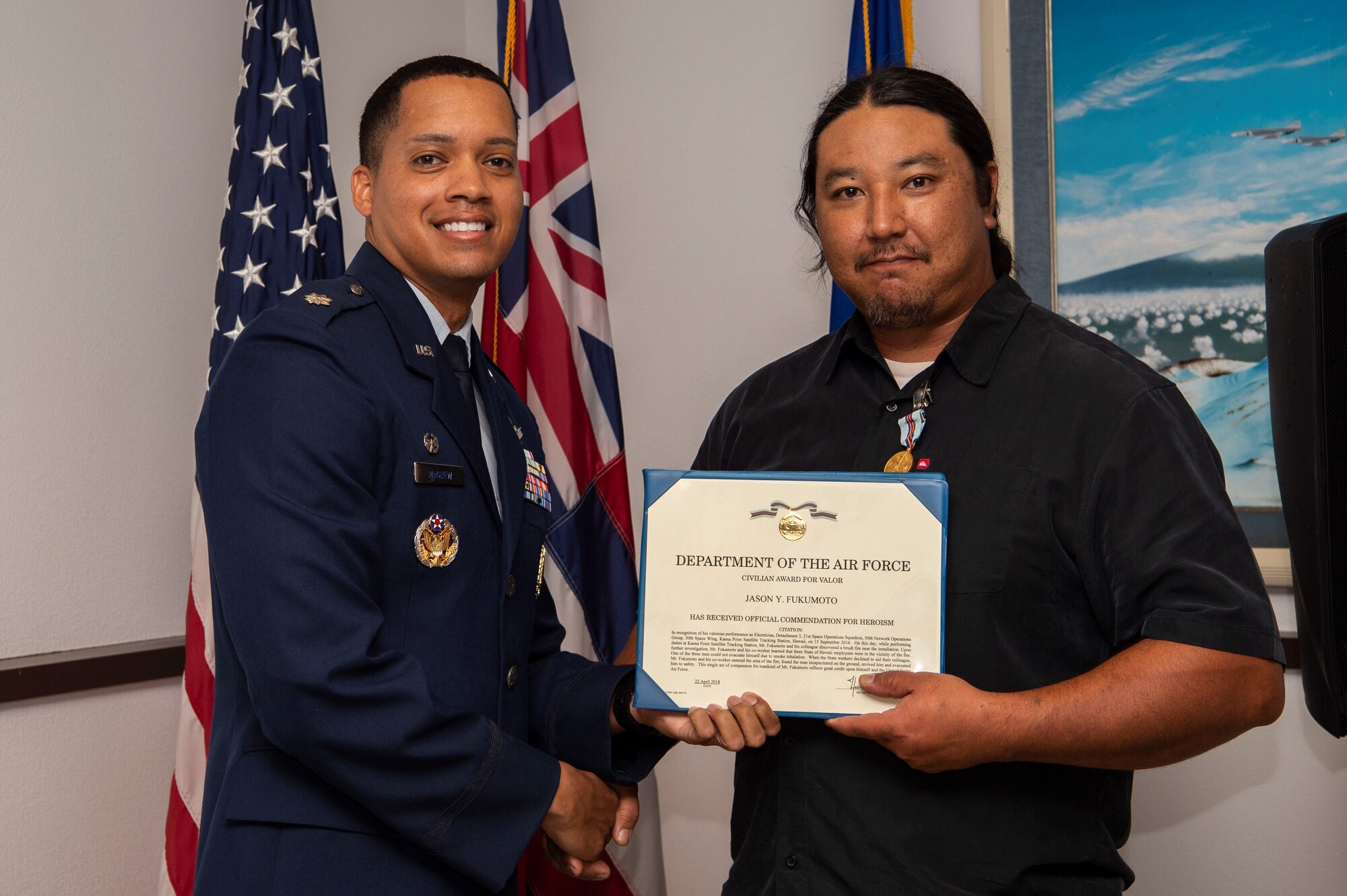 Lt. Col. Wade McGrew, 21st Space Operations Squadron commander, presents the Air Force Civilian Award for Valor to Jason Fukumoto, Detachment 3, 21st SOPS electrician, at the Kaena Point Satellite Tracking Station, Hawaii, July 23, 2018. Two years ago, Fukumoto provided medical aid to a state of Hawaii volunteer field crew member who suffered from smoke inhalation during a fire at the Kuaokala Game Management Area. (U.S. Air Force photo by Tech. Sgt. Heather Redman)