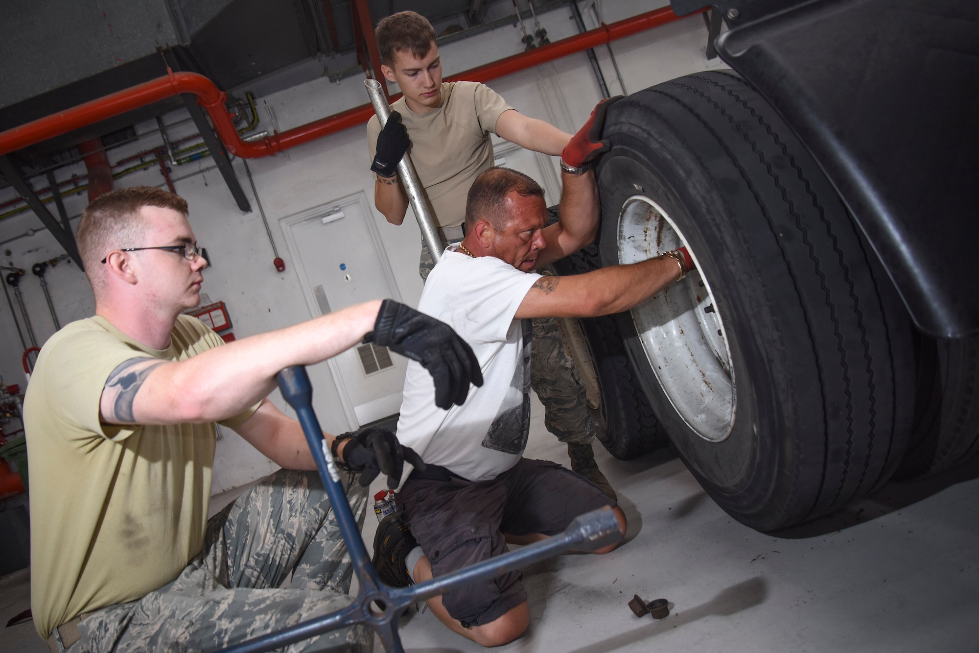 Andrew Crowie, 100th Logistics Readiness Squadron ground transportation operator, changes out a tire with the help of U.S. Air Force Airman 1st Class Brinkley Owens, and Airman 1st Class Dennis Fite, 100th LRS ground transportation operators, at RAF Mildenhall, England, July 18, 2018. Ground transportation operators have the ability to do minor maintenance to the vehicles they operate, but they work closely with 100th LRS Vehicle Management for any big repairs. (U.S. Air Force photo by Senior Airman Christine Groening)