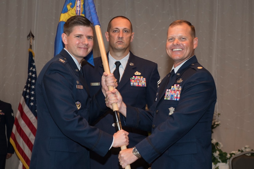 Lt. Col. Robert Clouse, right, 628th Security Forces Squadron outgoing commander, relinquishes command and passes the squadron’s guidon to Col. Rockie Wilson, left, 628th Mission Support Group commander, during a change of command ceremony July 23, 2018 at the Red Bank Club.