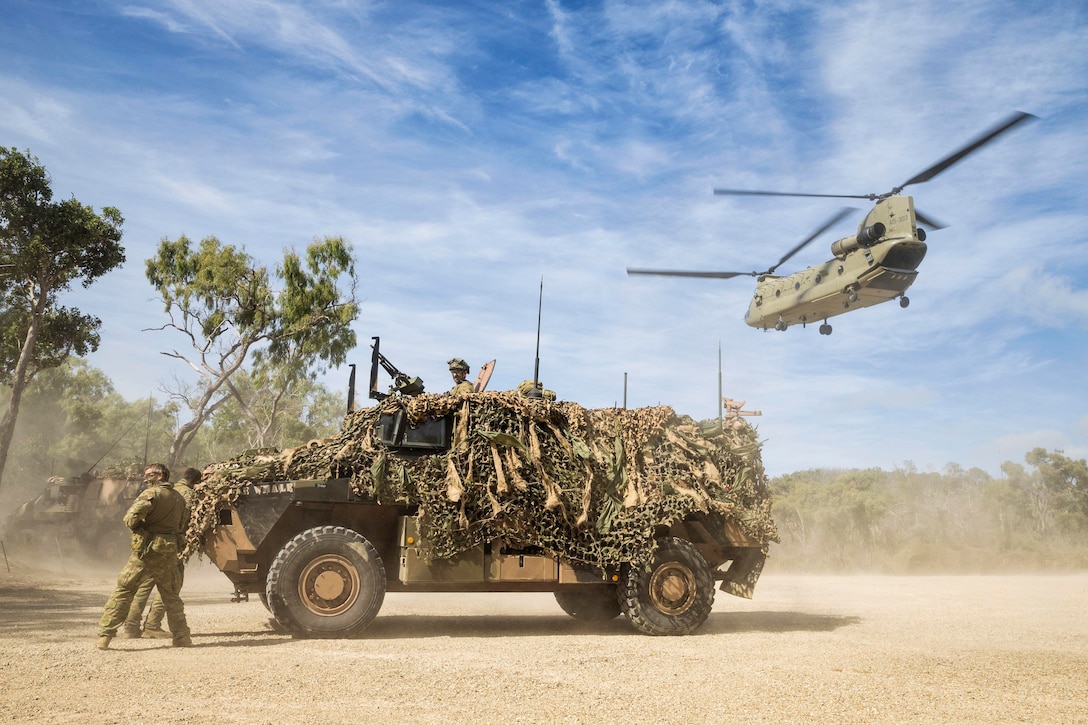 Soldiers take cover behind a vehicle.