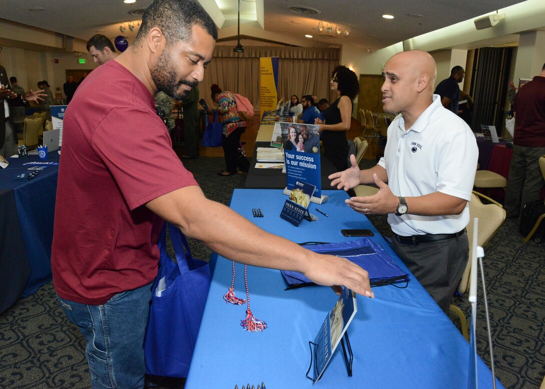 Izzy Avila, Penn State University outreach director (right), discusses his university's programs with a member of Team Edwards at the annual Education Fair held at Club Muroc July 24. (U.S. Air Force photo by Kenji Thuloweit)