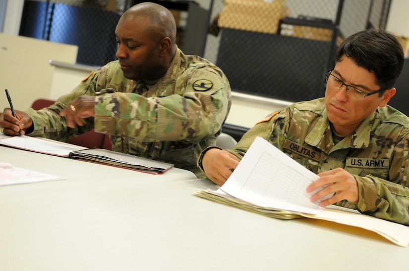 Sergeant 1st Class Chris Murray, information technology noncommissioned officer, 86th Training Division, and Staff Sgt. Jose Oblitas, information technology noncommissioned officer, 86th Training Division, review documents prior to signing for equipment from the 88th Readiness Division-operated Fort McCoy Draw Yard July 18.