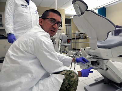 Lt. Cmdr. Nicholas Hamlin, Naval Medical Research Unit San Antonio Environmental Surveillance Department head and research dentist, demonstrates how an amalgam separator is attached to a dental chair and how it works in removing amalgam waste to prevent it from going into the wastewater system. Hamlin is part of a team of NAMRU-SA researchers who are involved in a project to develop a better prototype of the amalgam separator, a cylindrical device attached to a dental chair that filters amalgam, a mixture of metals including mercury, which is used by dentists for large teeth restorations and to fill in cavities.